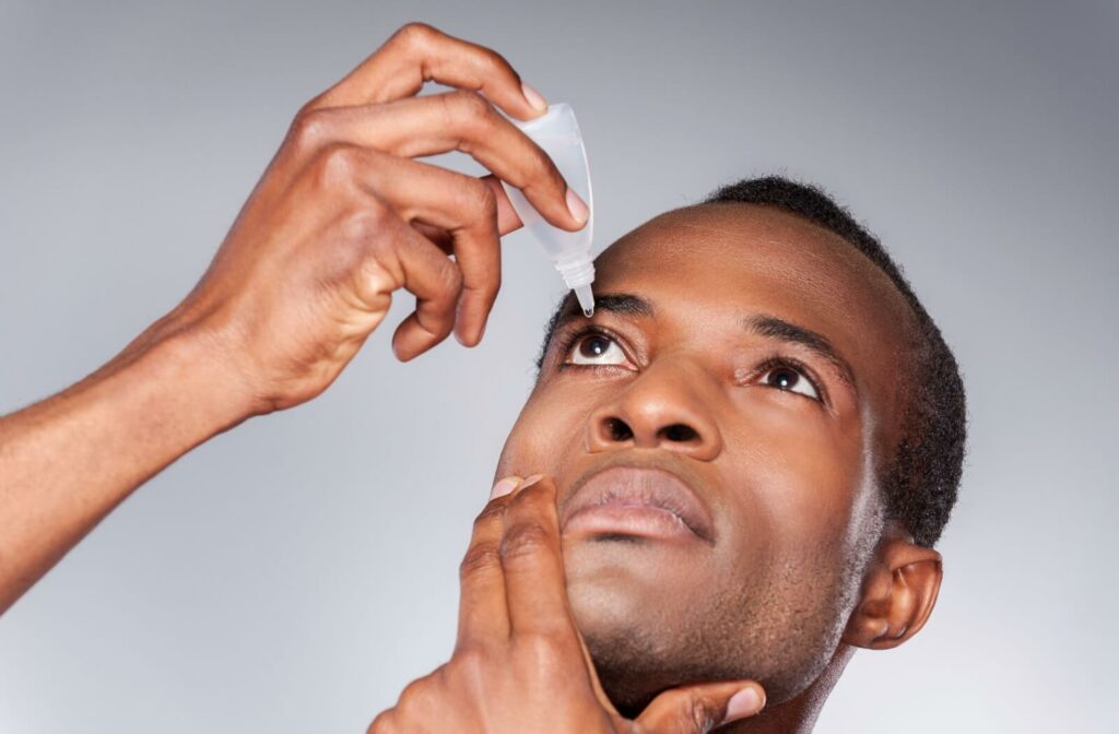 A man applying eyedrops to his right eye to lubricate his dry eye.