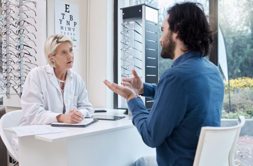 An optometrist across the desk from her patient listening carefully as he describes his dry eye symptoms.
