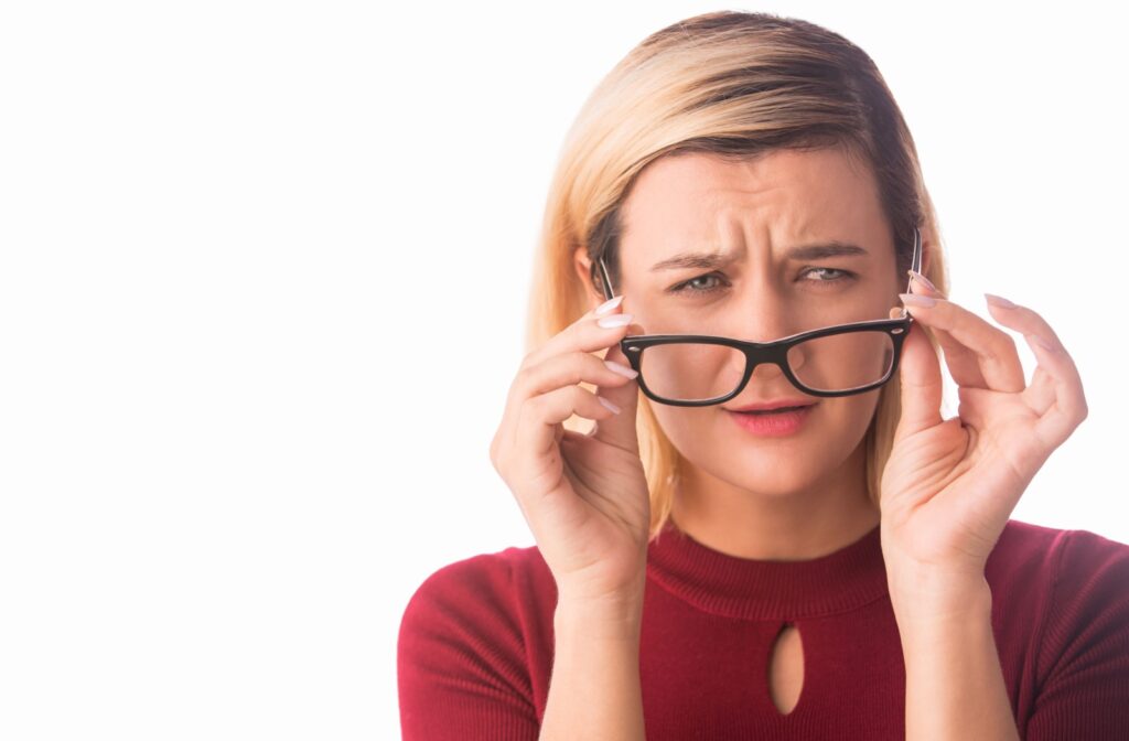 Person squinting and adjusting their glasses, looking confused or experiencing vision difficulty.