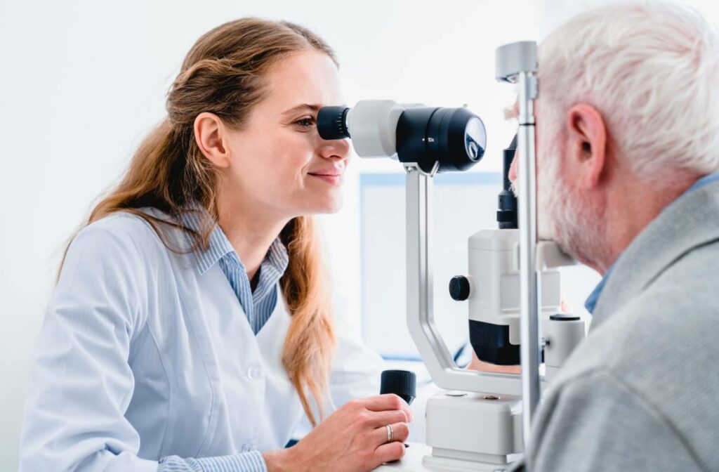 An optometrist examines an older adult's eyes using a slit-lamp microscope.