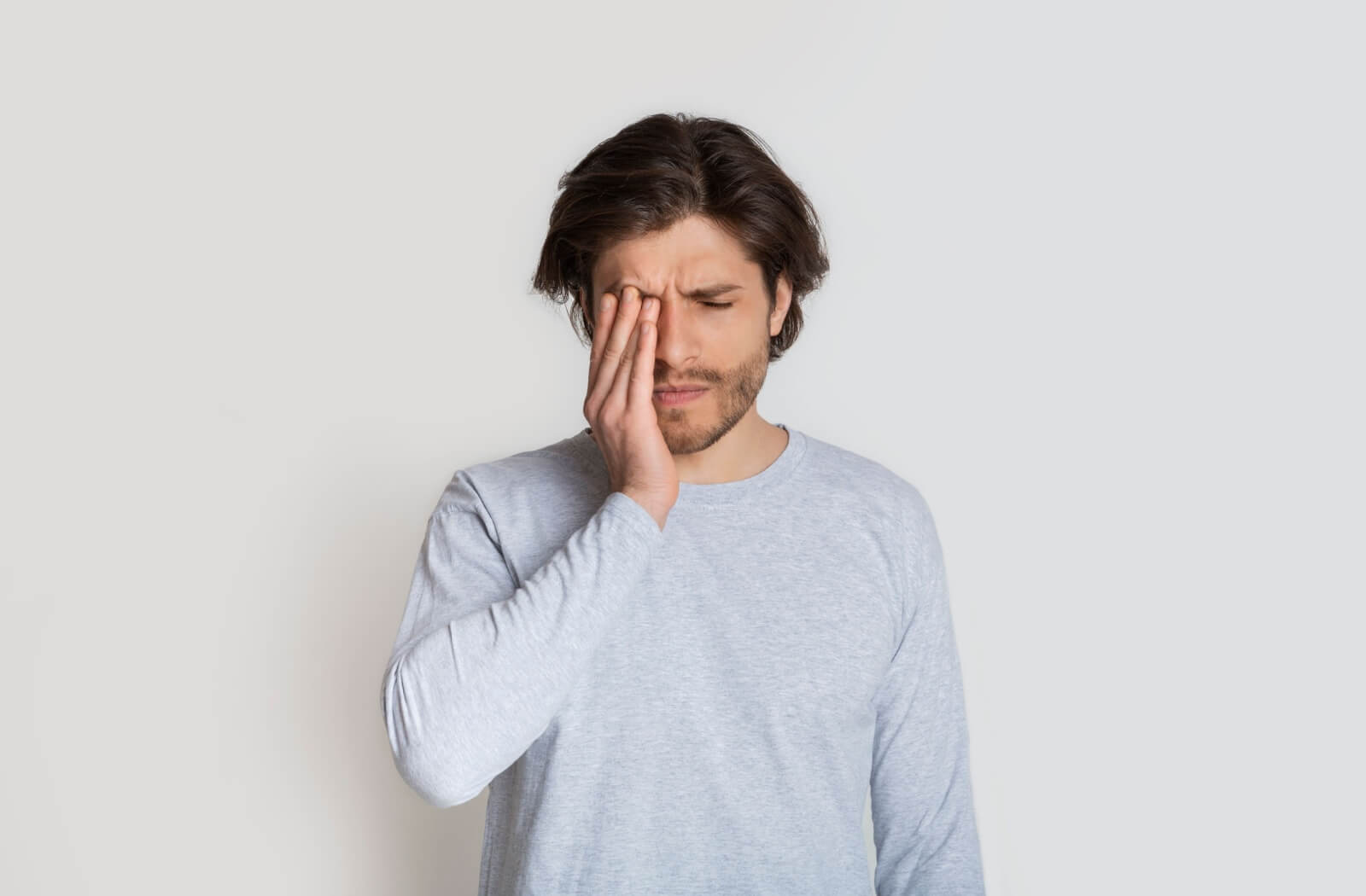 Man experiencing sudden eye pain and vision discomfort, a sign to seek emergency eye care.